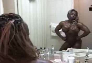 Black bodybuilder slut flexes muscles in front of the mirror