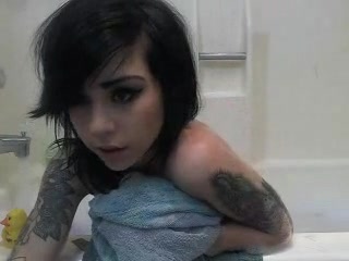 Dark-haired girl with tattoos having fun in the bathroom