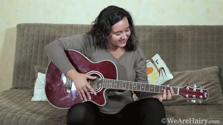 Ramira plays her guitar naked on her sofa