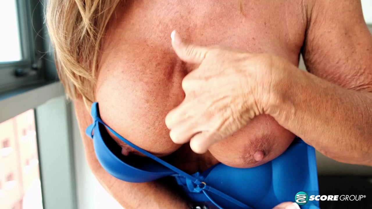A wife and granny with big, fake tits dips deep inside her pussy