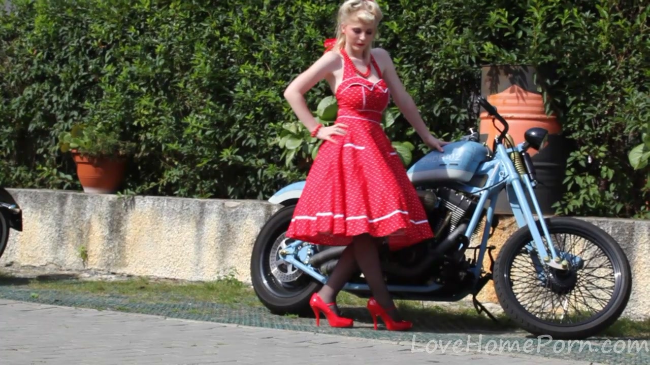 Cute blonde enjoys posing next to a bike