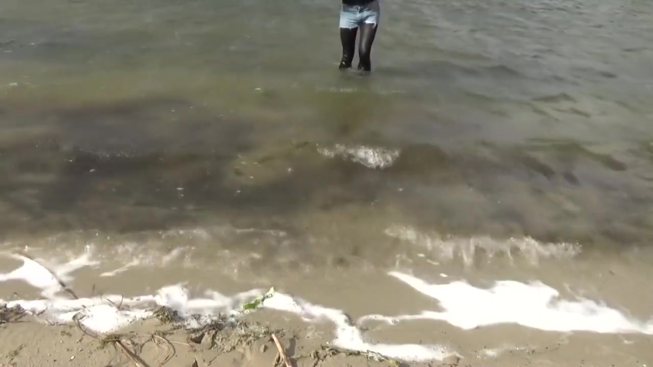 Sinthia in hot-pants wet-look leggings and heeled boots in a lake