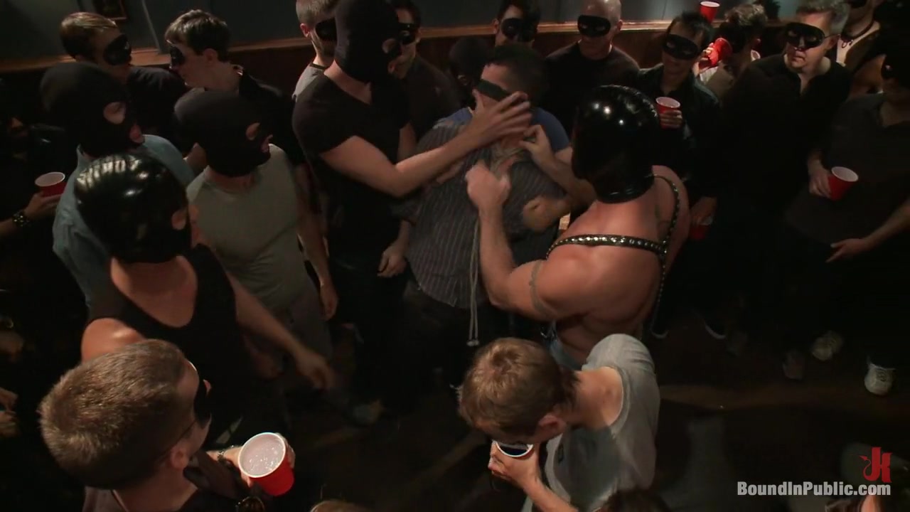 Captured stud is being used in a bar full of horny masked men