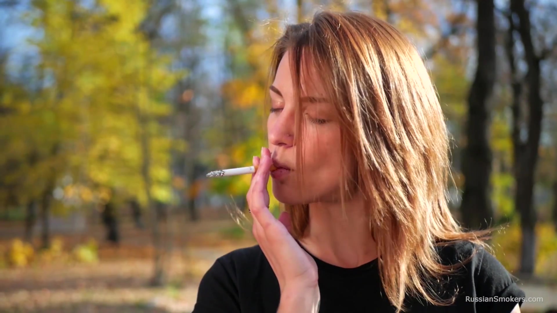 Sasha Is Smoking Two Cigarettes One By One In The Autumn Park