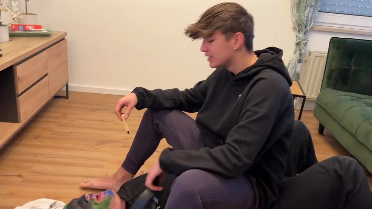 German master sitting on feet licking boy