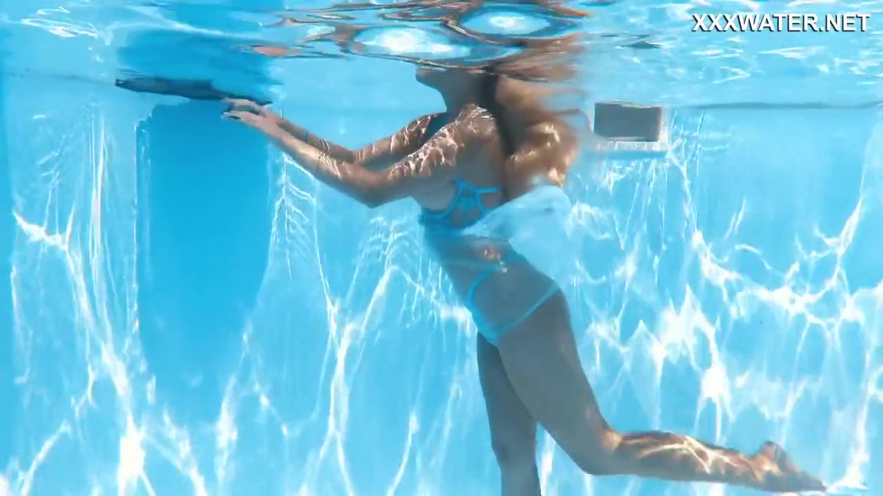 Her Body Cutting Through The Shimmering Water Of The Pool