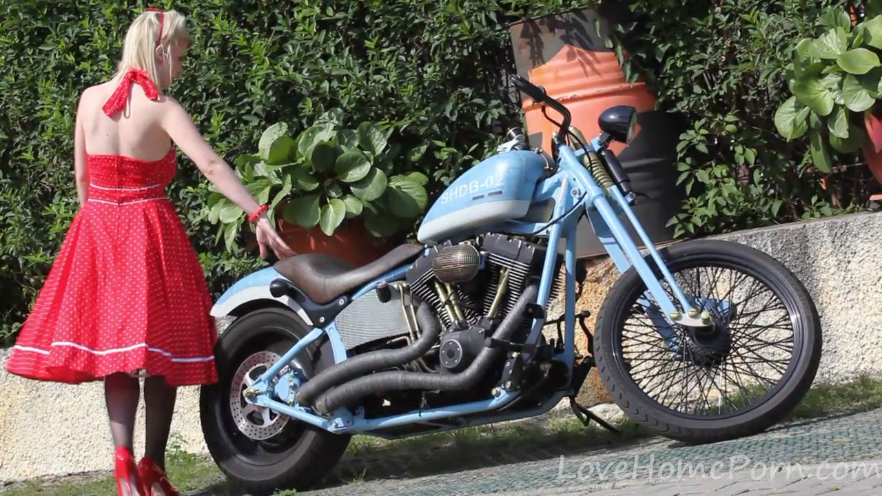Cute blonde enjoys posing next to a bike