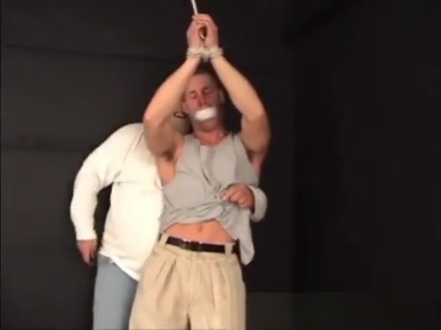 Handsome ex-military stud strung up by hs wrists gagged and stripped.