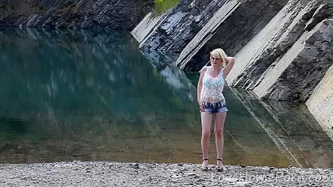 Busty blonde displays her figure near the lake