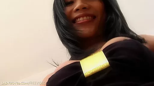 Brunette ladyboy in black dress strokes her long cock on the sofa